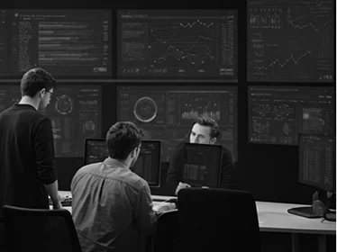 Een groep esports-analisten en teamleden die prestatiegegevens en wedstrijdstatistieken op meerdere grote aan de muur gemonteerde schermen bekijkt, waarbij ze tactische inzichten en spelergegevens bespreken in een moderne strategiekamer ontworpen voor competitieve gamevoorbereiding en besluitvormingsprocessen.