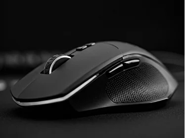 Close-up van een professionele draadloze gamingmuis geplaatst op een donker, gestructureerd bureaublad, met nadruk op de ergonomische vorm, precisie-scrollwiel en programmeerbare zijknoppen die vaak worden gebruikt door competitieve esports-spelers tijdens high-performance gameplay-sessies.